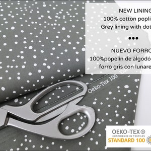 May include: Gray cotton poplin fabric with white dots. The fabric is folded in half and a pair of silver scissors are on top of the fabric. The fabric has a label that says "Oeko-Tex 100" and "NEW LINING! 100% cotton poplin Grey lining with dots" and "NUEVO FORRO! 100% popel&iacute;n de algod&oacute;n forro gris con lunares". The fabric also has a label that says "OEKO-TEX&reg; CONFIDENCE IN TEXTILES STANDARD 100".