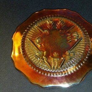 May include: A vintage iridescent glass dish with a scalloped edge and a design of four stylized swords with a central floral motif.