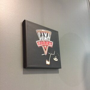 May include: A black sign with a red and white logo for Five Points Pizza. The logo is a triangle with the words "Five Points Pizza" inside.