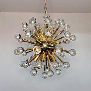 May include: A gold-toned Sputnik chandelier with multiple arms extending from a central sphere. Each arm holds a clear glass globe, creating a starburst effect. The fixture hangs from a chain.