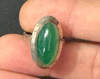 May include: A silver ring with a green oval gemstone set in a textured bezel.