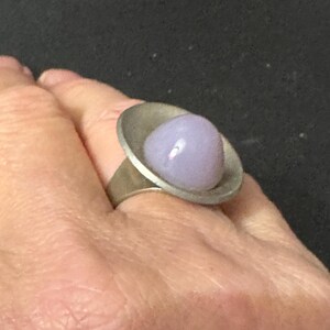 May include: A silver ring with a lavender glass cabochon set in a wide band.