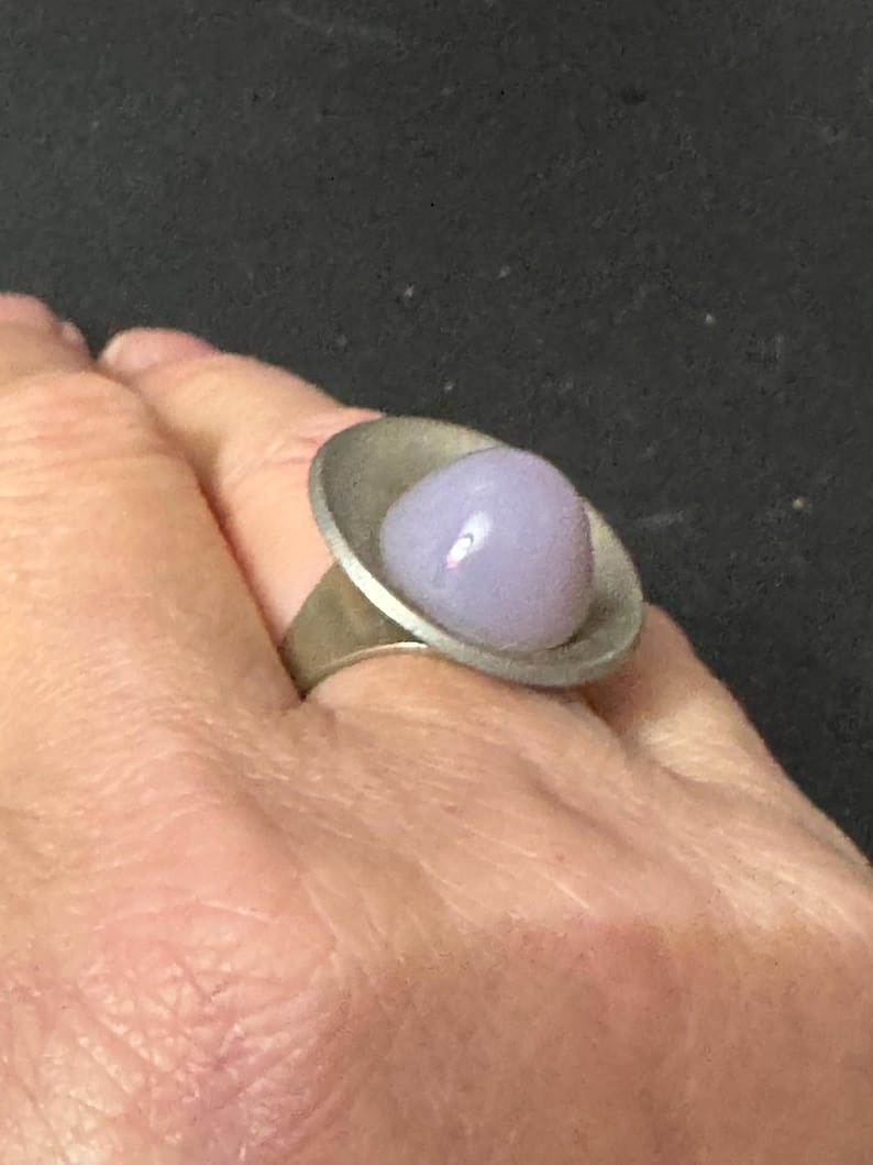 May include: A silver ring with a lavender glass cabochon set in a wide band.