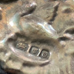 Puede incluir: Primer plano de un sello de plata con un le&oacute;n, una corona y una letra 'C'.