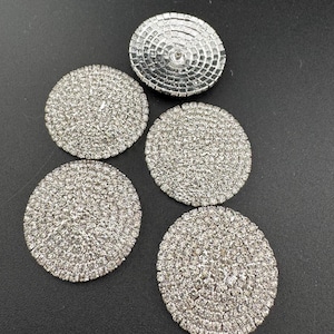 May include: Four silver round rhinestone embellishments with a single silver round embellishment with a hole in the centre.