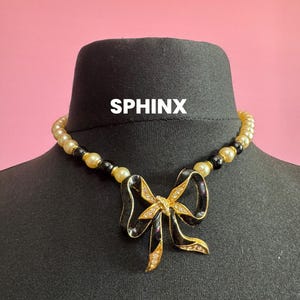 Signed Sphinx cream glass beaded diamanté necklace with classic black ribbon bow detail