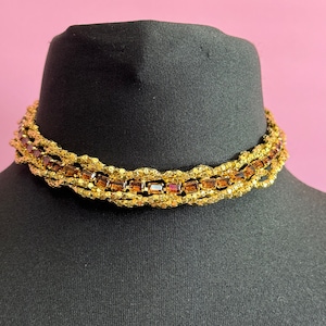 May include: A gold chain necklace with brown square-shaped rhinestones. The necklace is layered and has a twisted design.