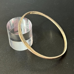 May include: A simple silver bangle bracelet. The bracelet is smooth and has a polished finish.