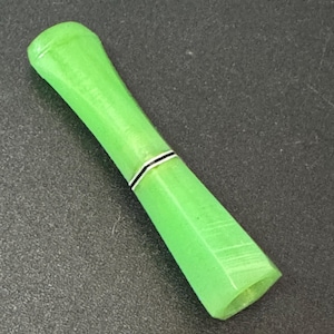 May include: A green cigarette holder with a black band around the middle.