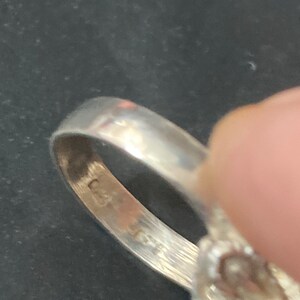 May include: Close-up of the inside of a silver ring with a floral design. The ring is marked with the number "925" on the inside band.
