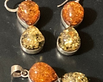 May include: A set of amber earrings and a pendant necklace. The earrings are silver with two amber drops each, one orange and one yellow. The pendant is silver with two amber drops, one orange and one yellow.