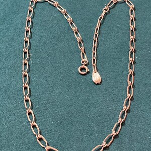 May include: A silver chain necklace with a lobster clasp closure. The chain is made of small, oval-shaped links.