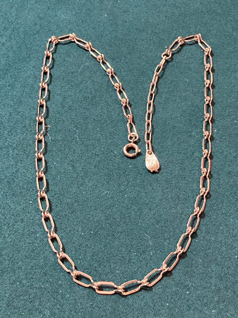 May include: A silver chain necklace with a lobster clasp closure. The chain is made of small, oval-shaped links.