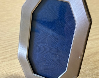May include: A silver octagonal picture frame with a blue patterned backing.