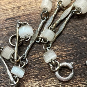 Pu&ograve; includere: Un braccialetto a catena d'argento con perline di vetro trasparenti. La catena &egrave; composta da pi&ugrave; fili di metallo intrecciato.