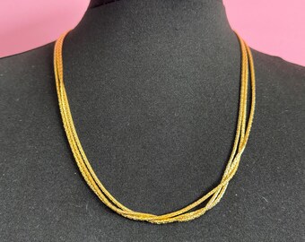May include: A gold multi-strand chain necklace with a delicate, textured design.