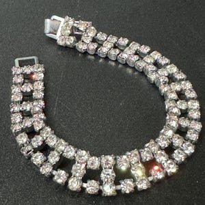 May include: A silver tone bracelet with a double row of clear rhinestones set in a geometric pattern.