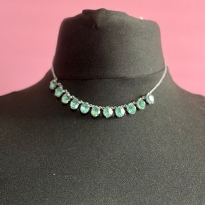 May include: A silver necklace with a row of oval-shaped, light blue gemstones.