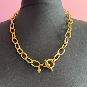 May include: A gold chain necklace with a toggle clasp and a small heart charm.