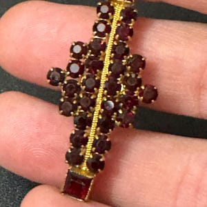 May include: A gold brooch with a cluster of red garnet stones in a geometric design.