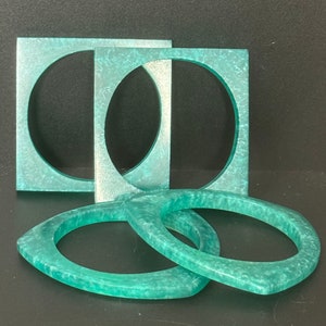 Peut inclure: Ensemble de quatre bracelets en plastique vert turquoise, deux carrés et deux ovales.