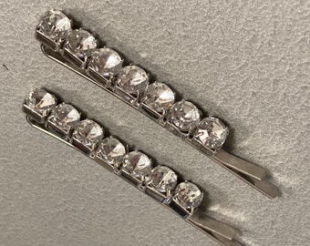 May include: Two silver hair clips with rows of clear rhinestones.
