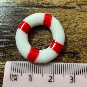 May include: A white and red striped life preserver ring measuring approximately 2 cm in diameter.