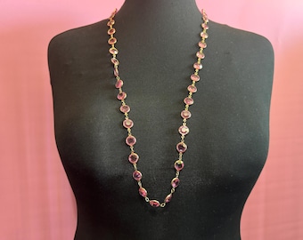 May include: A long pink and gold necklace with round pink stones.