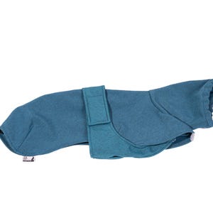 Pu&ograve; includere: Un cappotto per cani color verde acqua caratterizzato da un colletto alto, una sezione centrale avvolgente con cinturino a strappo e una piccola etichetta rettangolare del marchio fissata sull'orlo inferiore dell'indumento.