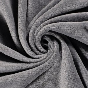 May include: A composite image showing three sections of soft, plush fleece fabric in solid colors. The top section is light beige, the middle section is medium gray, and the bottom section is black. Each fabric piece is arranged in a spiral.