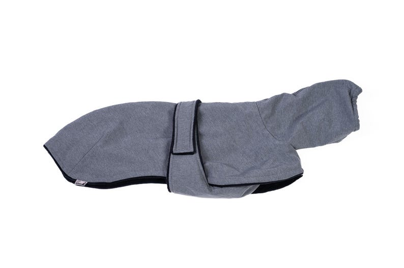 May include: A grey pet coat featuring a hood and a central strap with a hook-and-loop closure. The garment is constructed from a heathered grey fabric with black trim along the edges, providing a structured fit for an animal's torso and head.