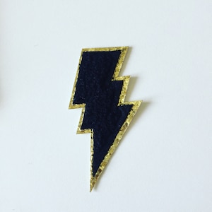 May include: A black felt lightning bolt patch with a gold glitter outline.