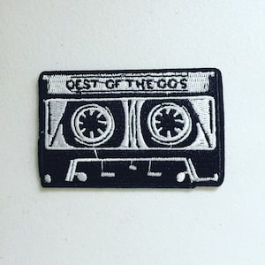 May include: Black and white embroidered patch in the shape of a cassette tape. The patch features the text "BEST OF THE 90'S" in white lettering. The cassette tape design includes two circular reel details.