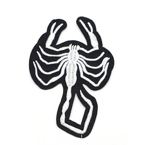 May include: Black and white embroidered iron-on patch of a scorpion.