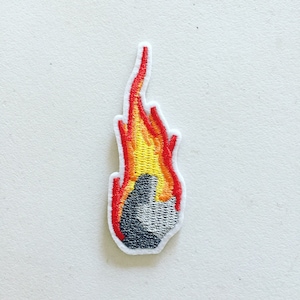 Può includere: Toppa ricamata da stirare con un design di roccia grigia con una fiamma rossa e gialla.