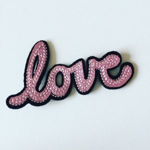 May include: Pink embroidered "LOVE" patch with black outline.
