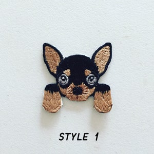 May include: Embroidered iron-on patch of a black and brown chihuahua with big eyes looking up. The patch has a brown background and the text "STYLE 1" is printed below the image.