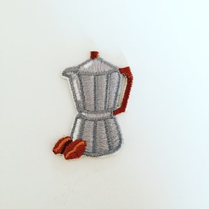 May include: Embroidered iron-on patch of a silver-colored coffee pot with a red handle and two brown coffee beans.