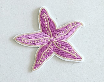 May include: A pink and gold embroidered starfish patch. The starfish is outlined in gold and has a dotted pattern.