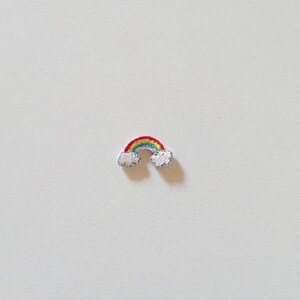 Può includere: Una piccola toppa ricamata a forma di arcobaleno. Presenta i colori vivaci rosso, arancione, giallo, verde, blu e viola. Nuvole bianche e soffici a ogni estremità. Per abbigliamento o accessori.