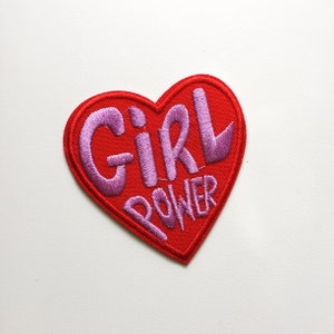 May include: Red heart-shaped patch with pink embroidered text that reads "Girl Power".