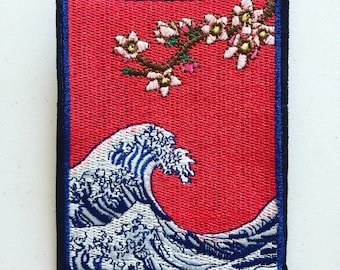 May include: Embroidered patch featuring a blue and white wave with a red background and a branch of pink and white flowers.