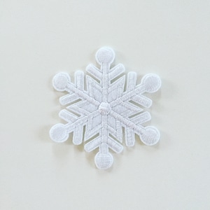 Peut inclure: Patch brodé en forme de flocon de neige blanc. Le flocon de neige est détaillé avec des points de couture complexes et a une texture légèrement en relief.