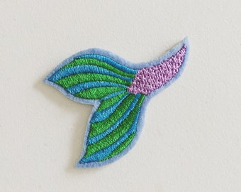 May include: A blue, green, and purple embroidered mermaid tail patch. The tail is made of felt and has a striped pattern.