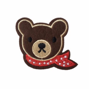 May include: Brown embroidered bear face with a red and white polka dot scarf.