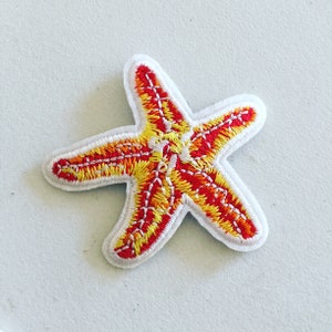 May include: An embroidered starfish patch in red and yellow. The starfish is white with red and yellow stitching.