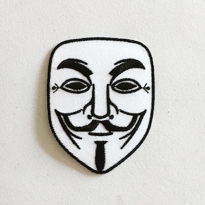 May include: A white embroidered patch with a black outline of the iconic Anonymous mask. The mask features a stylised face with a wide smile, a moustache, and a goatee.