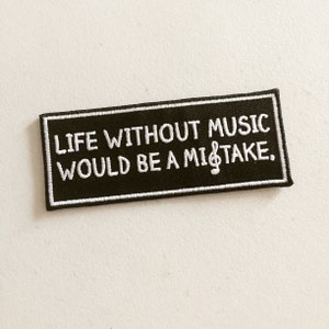 Könnte beinhalten: Schwarz-weiß gestickter Patch mit dem Text "Life without music would be a mistake." und einem Violinschlüssel.