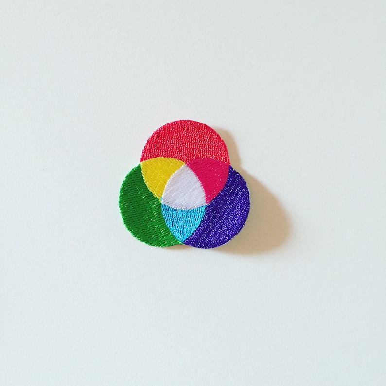 Op de afbeelding: Een kleurrijk geborduurd patch met overlappende cirkels in rood, geel, wit, blauw en groen.