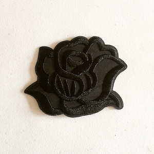 Peut inclure: Patch thermocollant brodé noir d'une seule rose.
